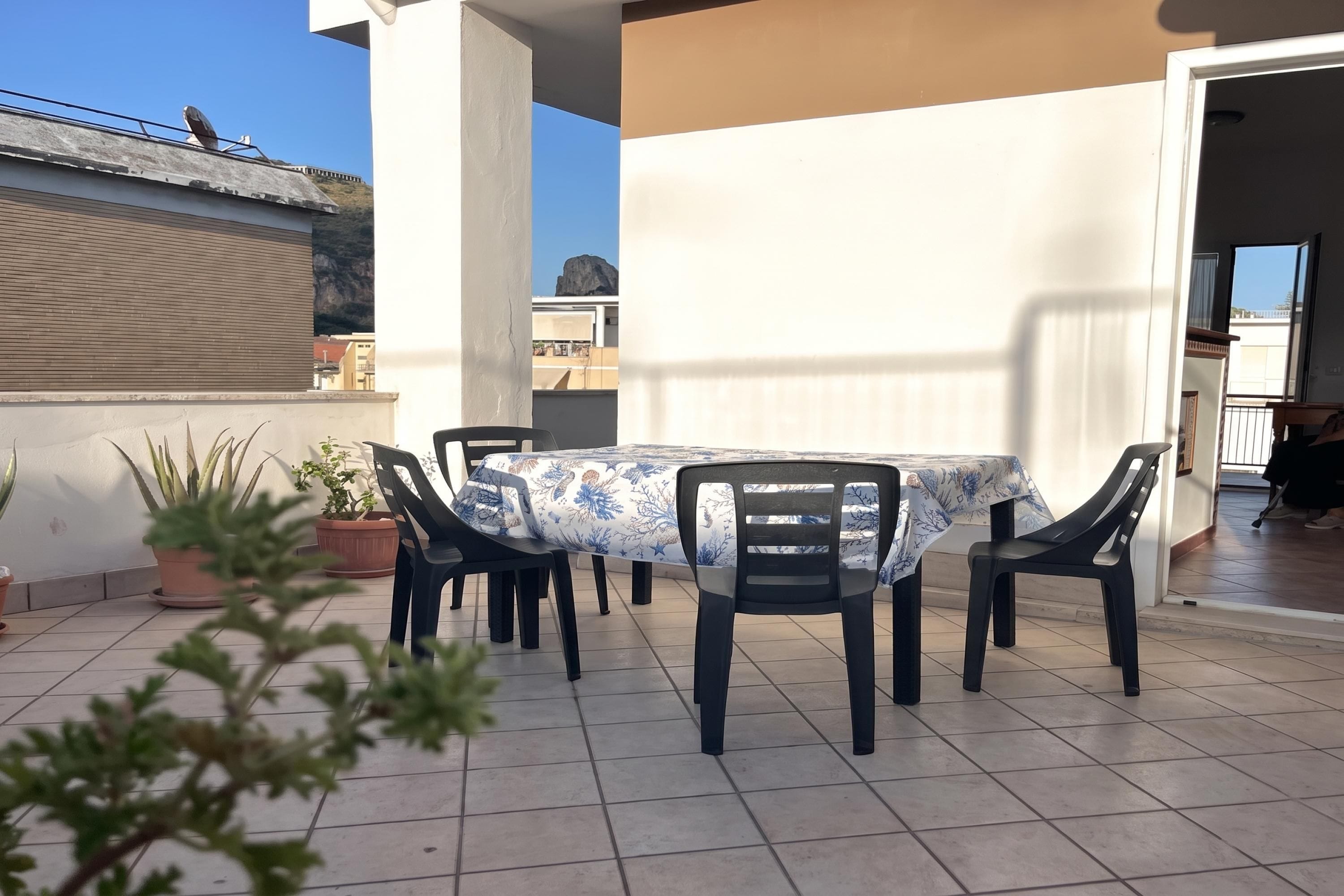 Une terrasse extérieure avec une table et des chaises, des plantes en pot et une vue sur les environs.