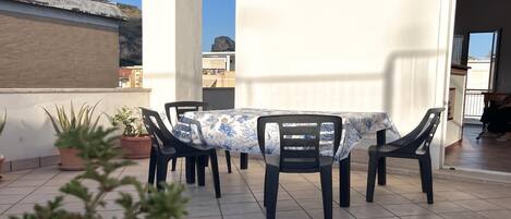 Une terrasse extérieure avec une table et des chaises, des plantes en pot et une vue sur les environs.