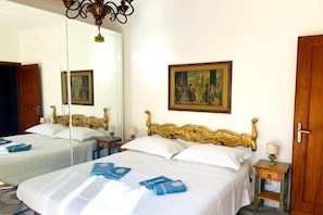 A hotel room with two beds, a large mirror, a painting on the wall, and a wooden door. - Appartamento Mare Blu - Terracina (Terracina)