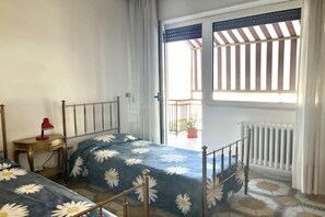 A bedroom with a bed, a nightstand, a window with a view, and a radiator. - Appartamento Mare Blu - Terracina (Terracina)