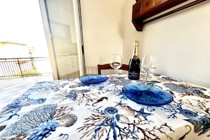 A dining table with a blue floral tablecloth, two wine glasses, and a bottle of champagne. - Appartamento Mare Blu - Terracina (Terracina)