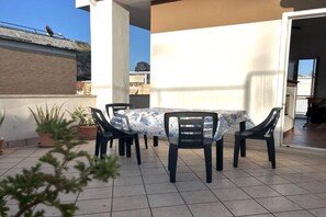 Une terrasse avec une table et des chaises, des plantes en pot et une vue sur les environs.