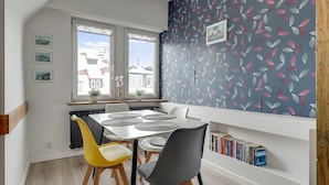 A dining area with a table, chairs, and a bookshelf. - Sopot 2 by Grand Apartments (Sopot)