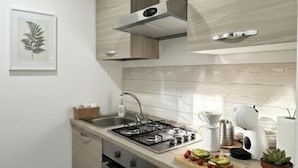 A modern kitchen with a gas stove, stainless steel sink, and wooden cabinets. - Residence Cicerone (Agrigento)