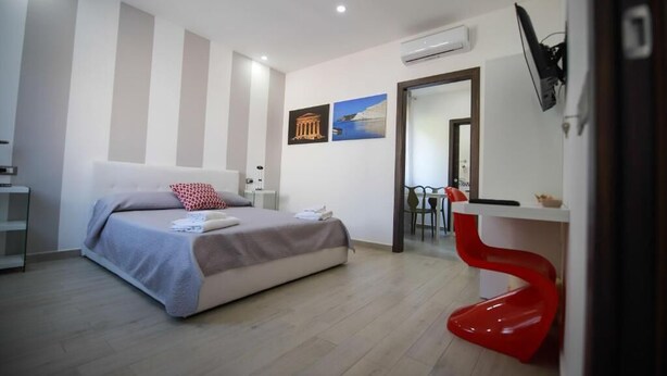A modern hotel room with a bed, a desk, and a red chair. - Residence Cicerone (Agrigento)