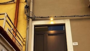 A residential building entrance with a dark wooden door, a staircase, and a sign for 'Cicerone Residence'. - Residence Cicerone (Agrigento)