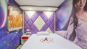 Een hotelkamer met een bed, nachtkastje, een televisie aan de muur en een groot poster.