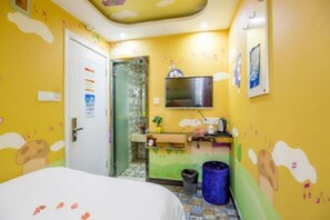 A room with a bed, a television, a sink, and a trash bin.