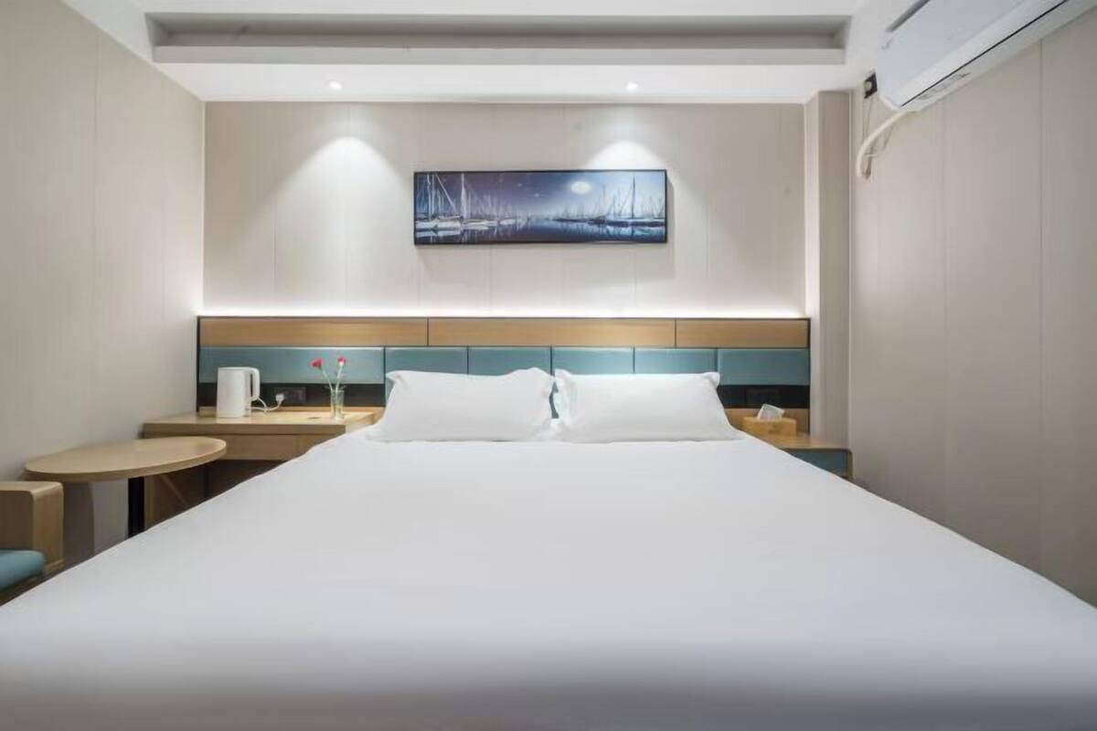 A hotel room with a large bed, a small desk, and a television mounted on the wall.