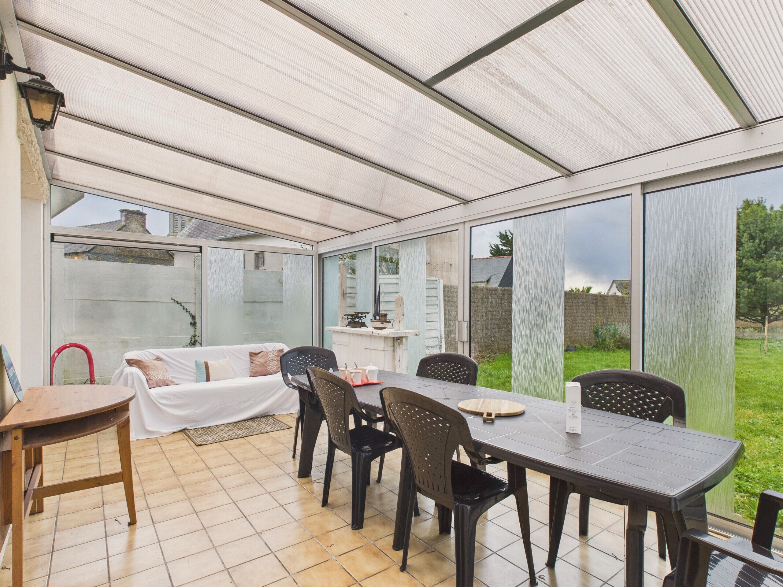 Eine überdachte Terrasse mit Esstisch und Stühlen, einer Couch und einer kleinen Küchenzeile.