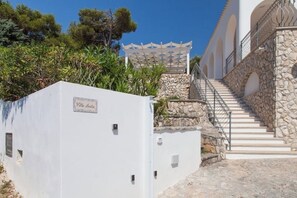 Un edificio bianco con una scala in pietra che conduce a una zona coperta.