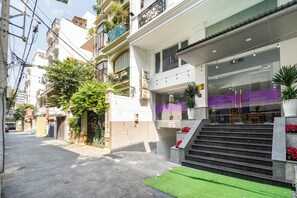 A hotel entrance with a staircase leading to the lobby, surrounded by buildings and greenery. - HELEN AIRPORT HOTEL (Ho Chi Minh City)