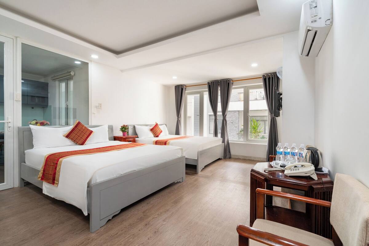 Habitación de hotel con dos camas, una mesita con teléfono y botellas de agua, y una silla.