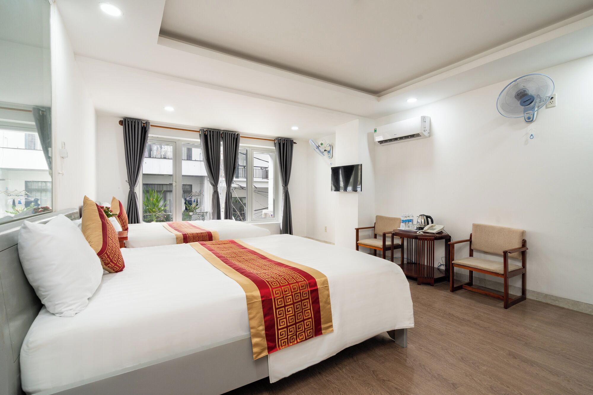 Una habitación de hotel con una cama grande, dos sillas, una mesita y un televisor.