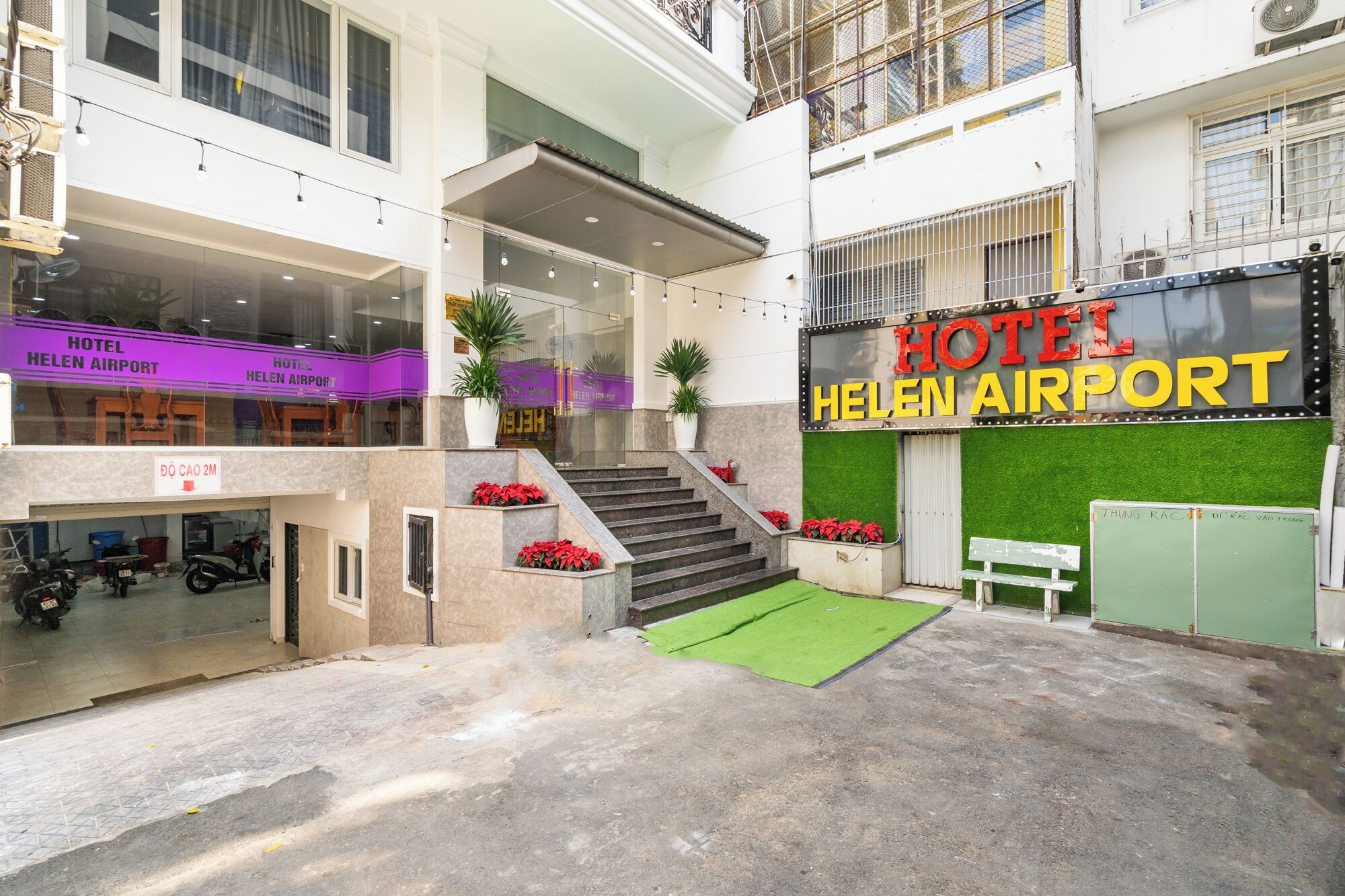 A hotel with a sign reading "HOTEL HELEN AIRPORT" and a staircase leading to an upper level.