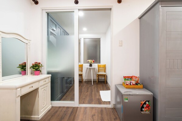 A compact kitchen with a refrigerator, a sink, and a window with frosted glass. - HELEN AIRPORT HOTEL (Ho Chi Minh City)