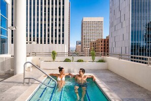 A rooftop pool with two people, surrounded by modern buildings and clear skies. - Stylish ASU Stay Pool Gym Balcony Parking WD (Phoenix)
