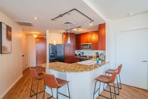 Eine moderne Küche mit Granit Arbeitsplatten, Edelstahlgeräten und Barhocker.