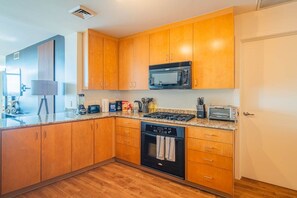 A modern kitchen with wooden cabinets, a microwave, a stove, and a dishwasher. - Sleek Downtown PHX High Rise City Views Top Am (Phoenix)