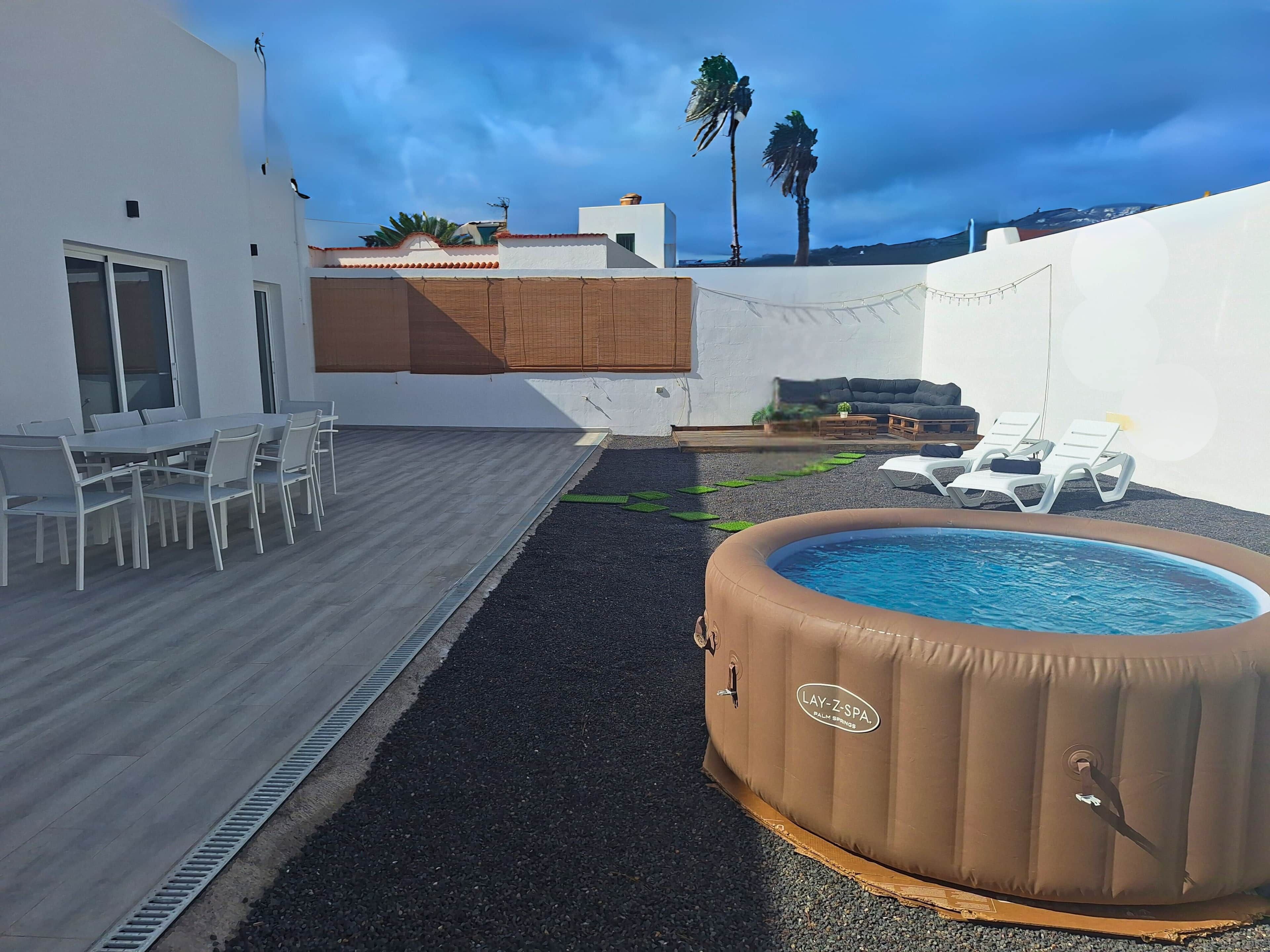 Eine Dachterrasse mit Whirlpool, Sitzgelegenheit im Freien und Blick auf Palmen.