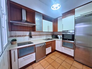 A modern kitchen with stainless steel appliances, wooden cabinets, and a tiled backsplash. - El Chaflán Apartment – Charming Apartment with Style (Santa Cruz de Tenerife)