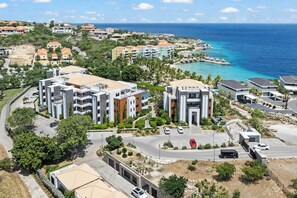 Zona residencial costera con edificios modernos, un estacionamiento y vista al océano.