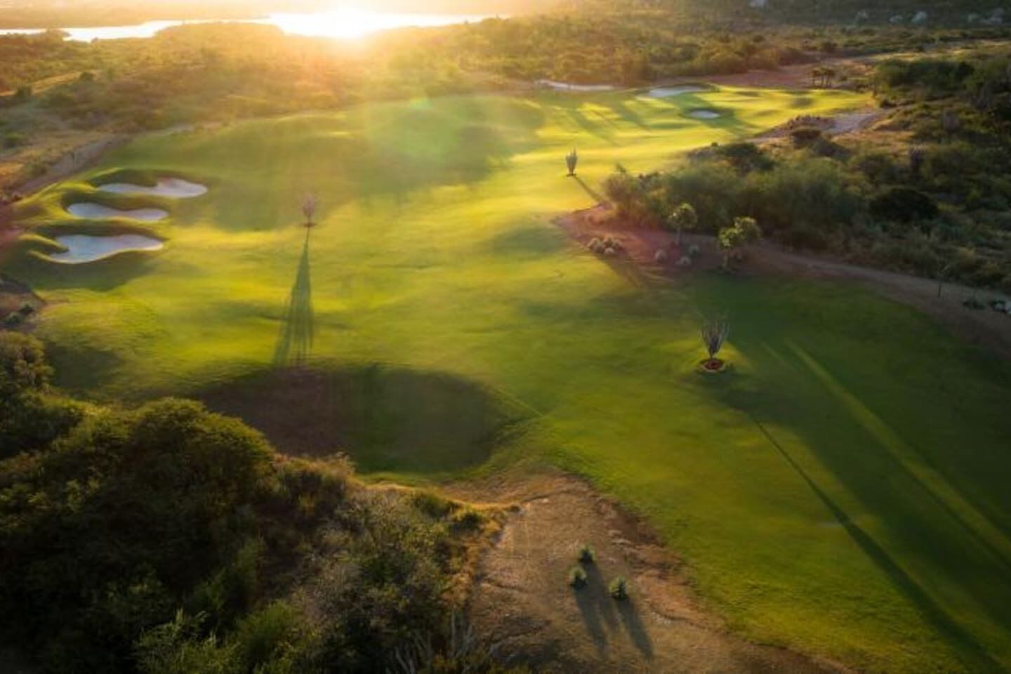 A golf course with sand bunkers, a putting green, and a flagstick.