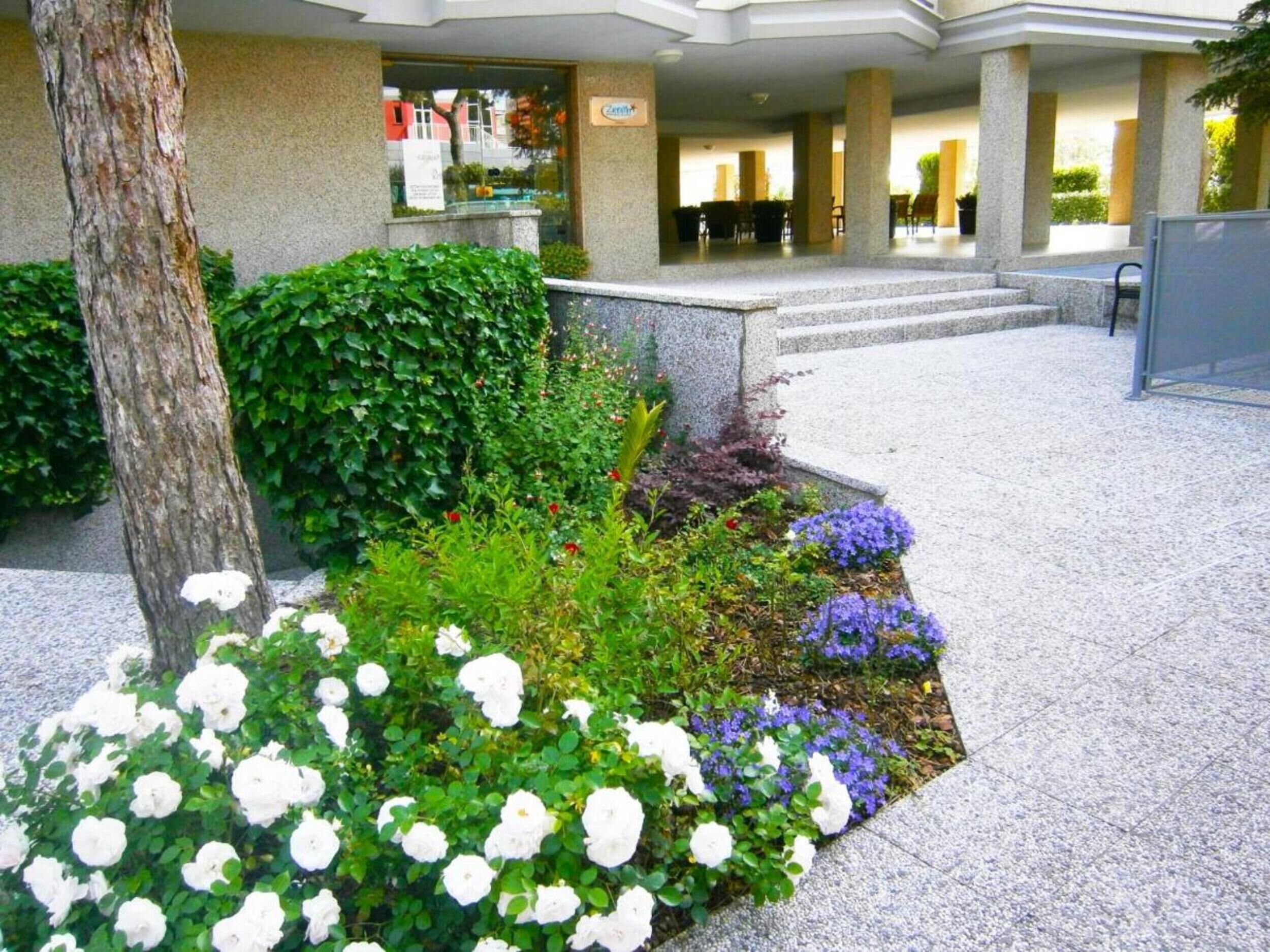 A hotel entrance with a stone pathway leading to a covered seating area.