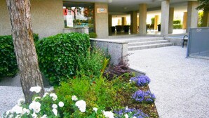 A hotel entrance with a stone pathway leading to a covered seating area.