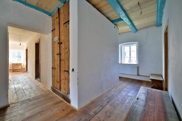 Une pièce avec un plancher en bois, une grande porte en bois et une fenêtre.