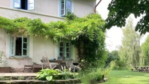 Una casa con un giardino, un tavolo e sedie all'esterno.