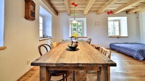 Un tavolo da pranzo in legno con sedie, un lampadario a sospensione e un orologio appeso al muro.