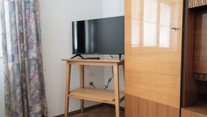 Un meuble en bois pour téléviseur, avec un téléviseur à écran plat, une télécommande et une prise de courant.