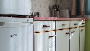 Une cuisine avec des meubles blancs, un réfrigérateur blanc et un plan de travail muni d’un porte-couteaux.