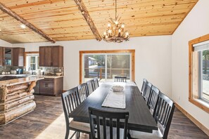 Une cuisine spacieuse avec un plafond en bois et une grande table à manger entourée de chaises.