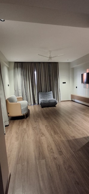 A spacious room with a large bed, a sofa, and a ceiling fan.