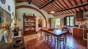 Una cucina rustica con pareti in mattoni a vista, travi in legno e un tavolo da pranzo tradizionale.