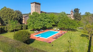 Una piscina circondata da poltroncine, una torre in pietra e una chiesa con una cupola.