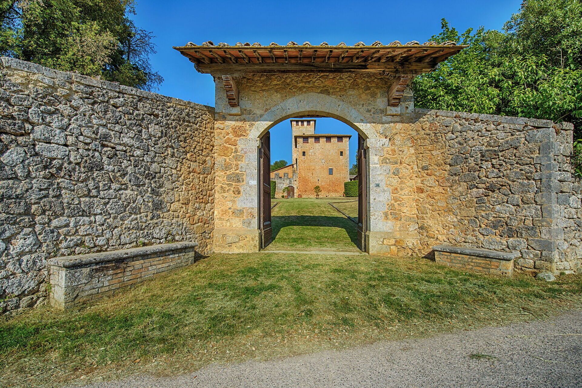 A stone archway leading to a castle with a tiled roof.