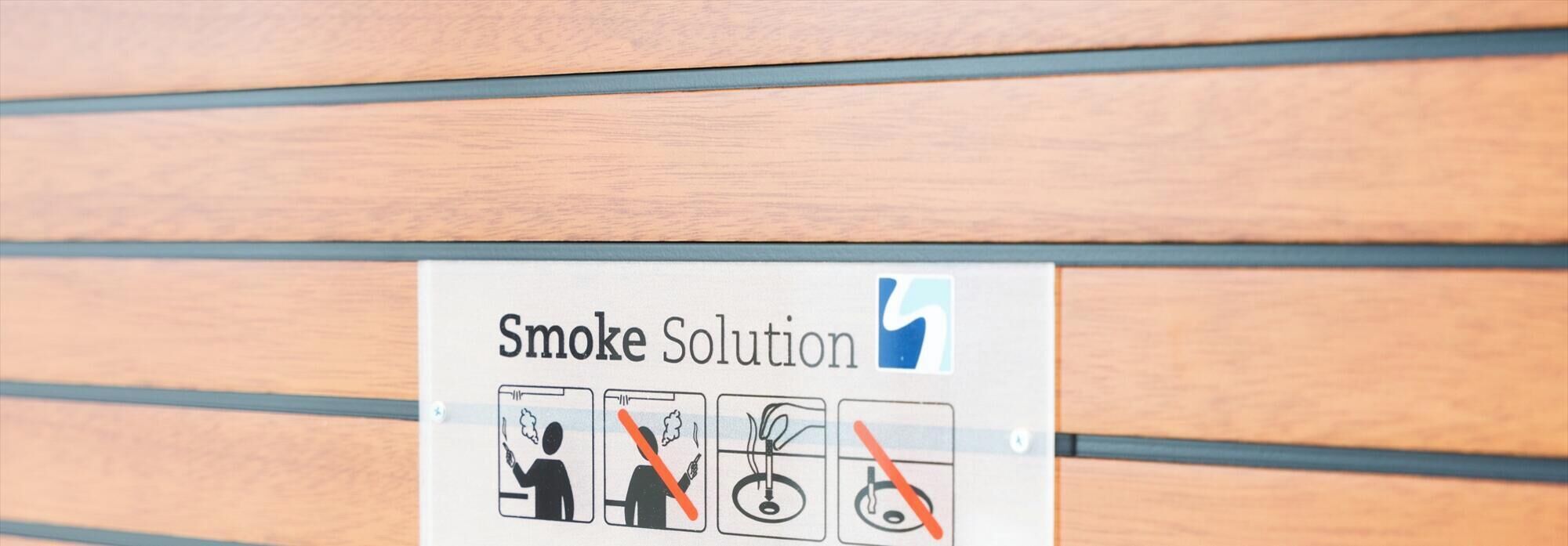 A sign with the text "Smoke Solution" and icons indicating no smoking, no smoking near the exit, no smoking in the bathroom, and no smoking in the kitchen.