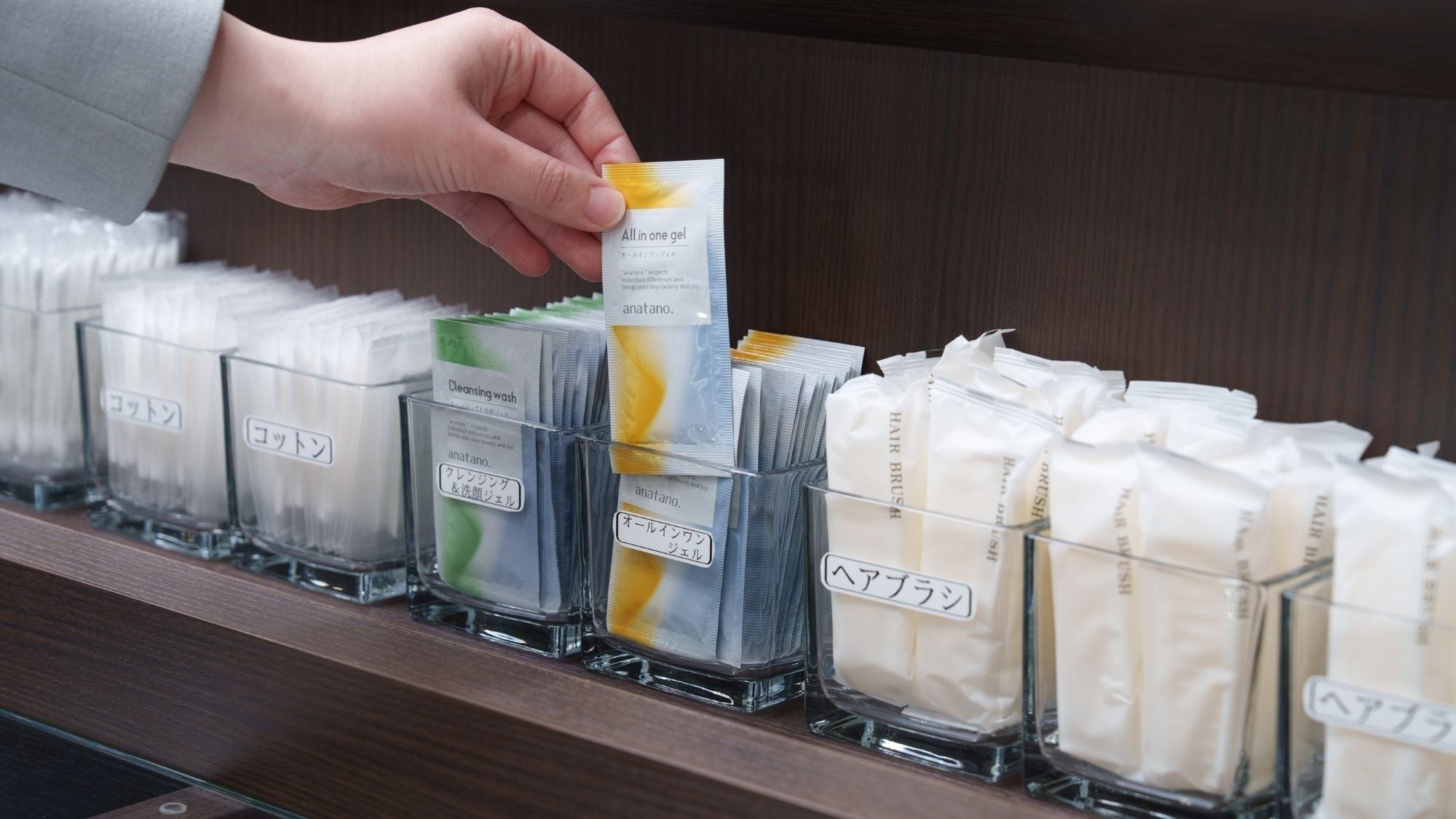 A hand selecting a product from a shelf with multiple compartments, each containing different items.