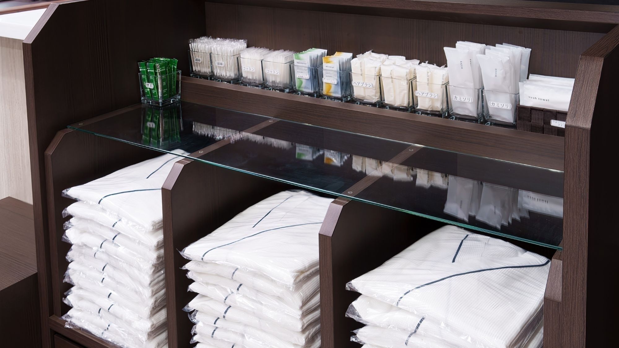 Zona de servicios de una habitación de hotel, con toallas y artículos de aseo ordenados en estantes.
