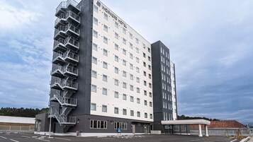 A multi-story hotel with a prominent fire escape, a covered entrance, and a parking lot.