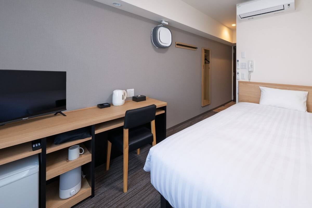 Ein Hotelzimmer mit einem Bett, einem Schreibtisch mit Fernseher, einer Kaffeemaschine und einem Spiegel.