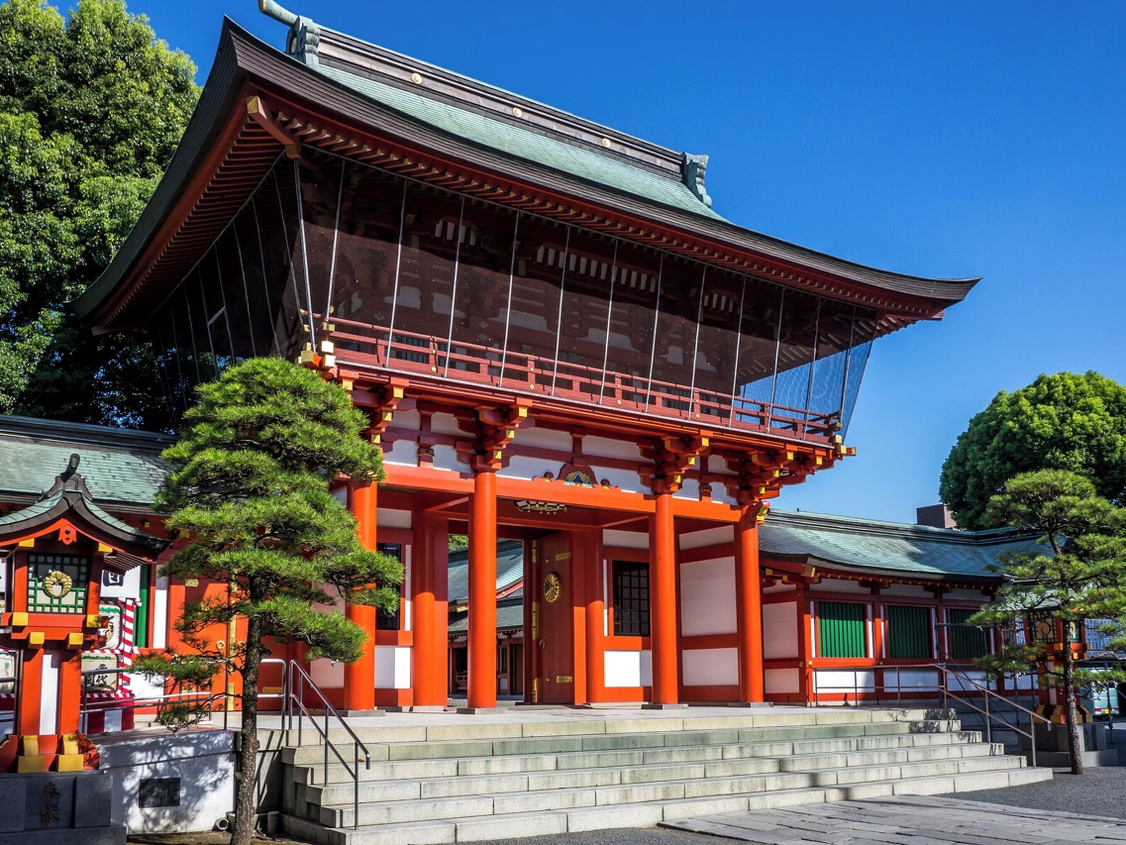 Un edificio japonés tradicional con techo curvo, pilares rojos y una escalera de piedra que conduce a la entrada.