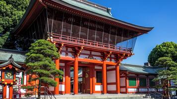 A traditional Japanese building with a curved roof, red pillars, and a stone staircase leading to the entrance.