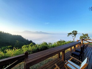 A wooden deck with seating overlooking a mountainous landscape and a view of the sky. - Workers Hotel Kumamoto Ozu (Ozu)
