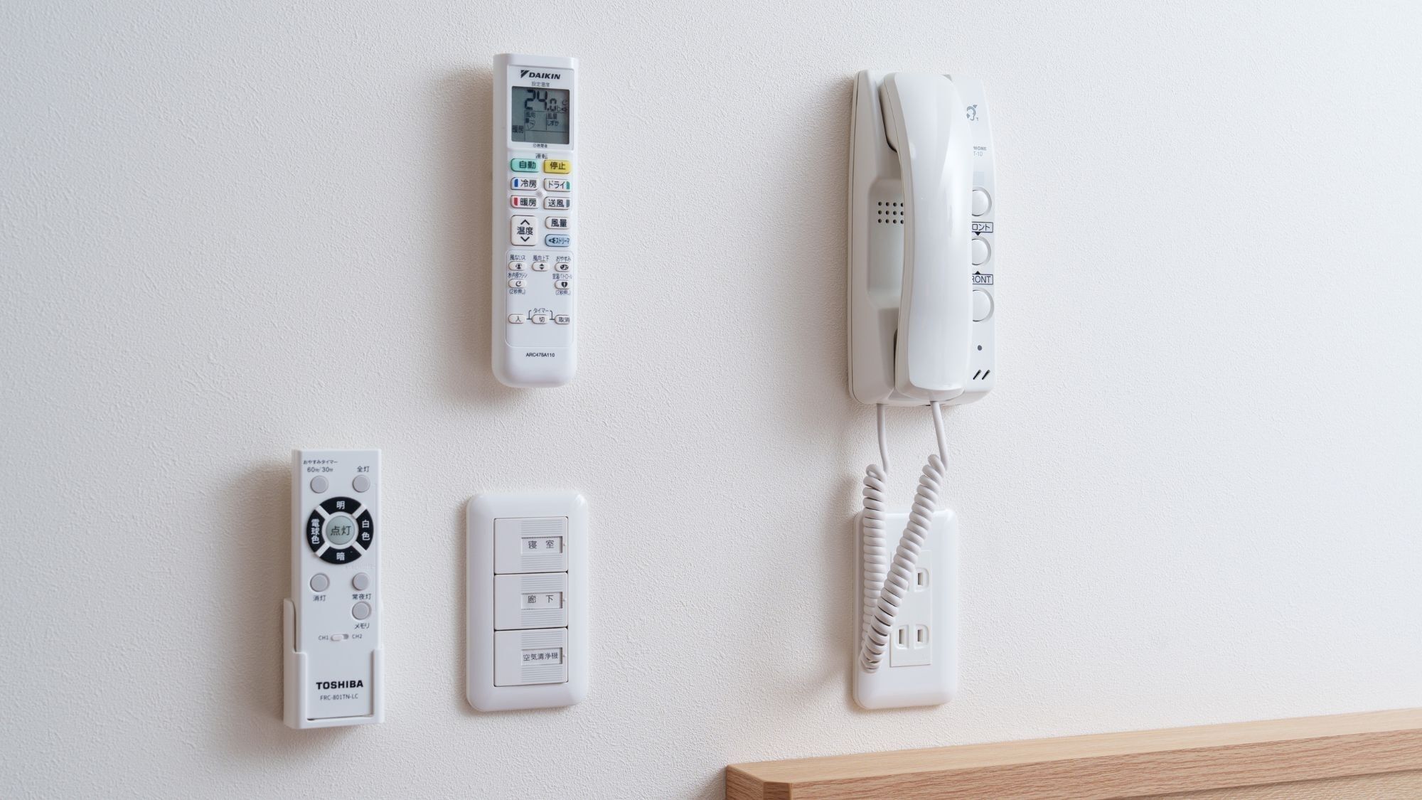 A wall-mounted thermostat, a wall-mounted telephone, a wall-mounted intercom, and a wall-mounted light switch.
