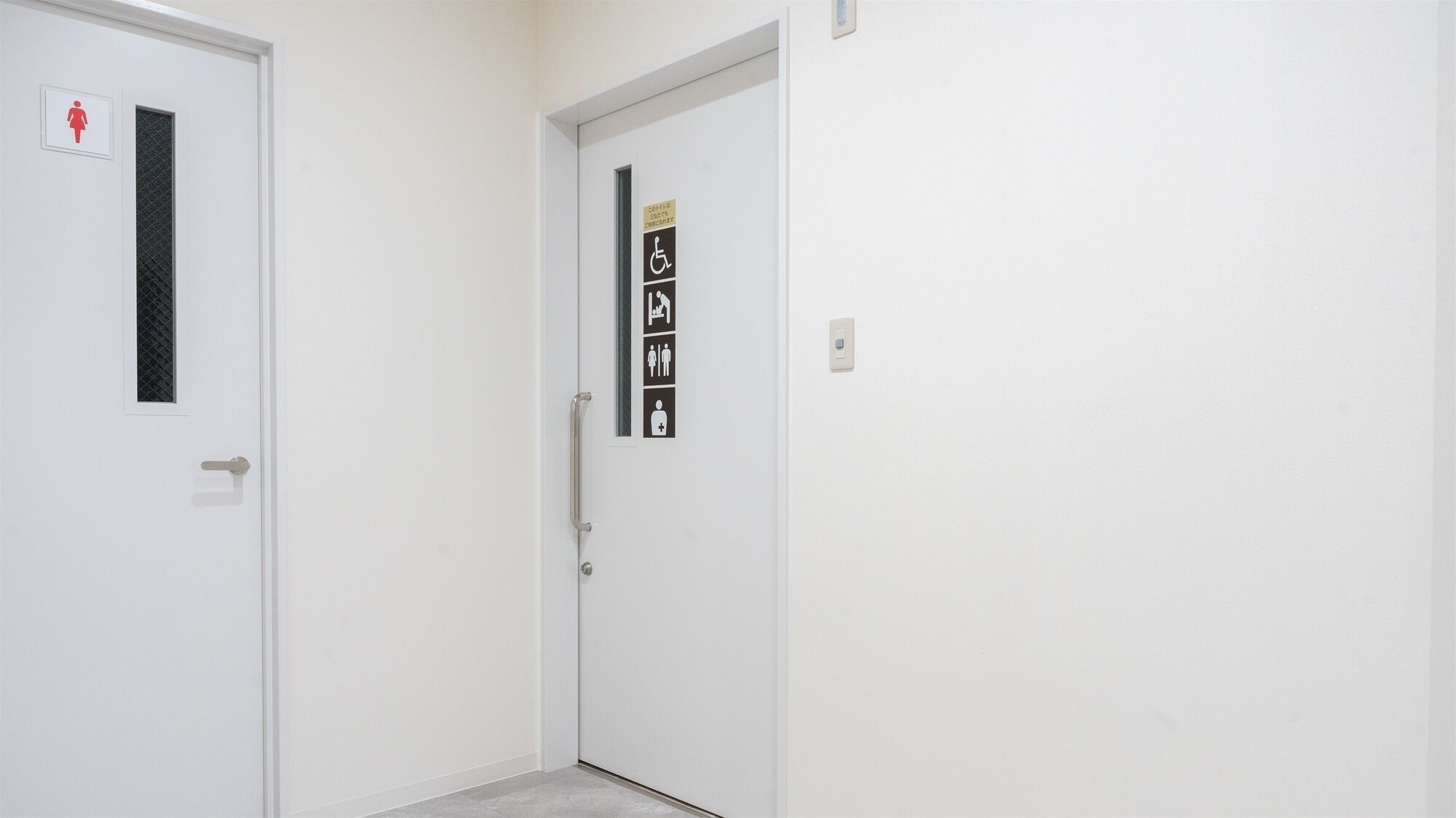 A white door with a small window and a red female restroom symbol.
