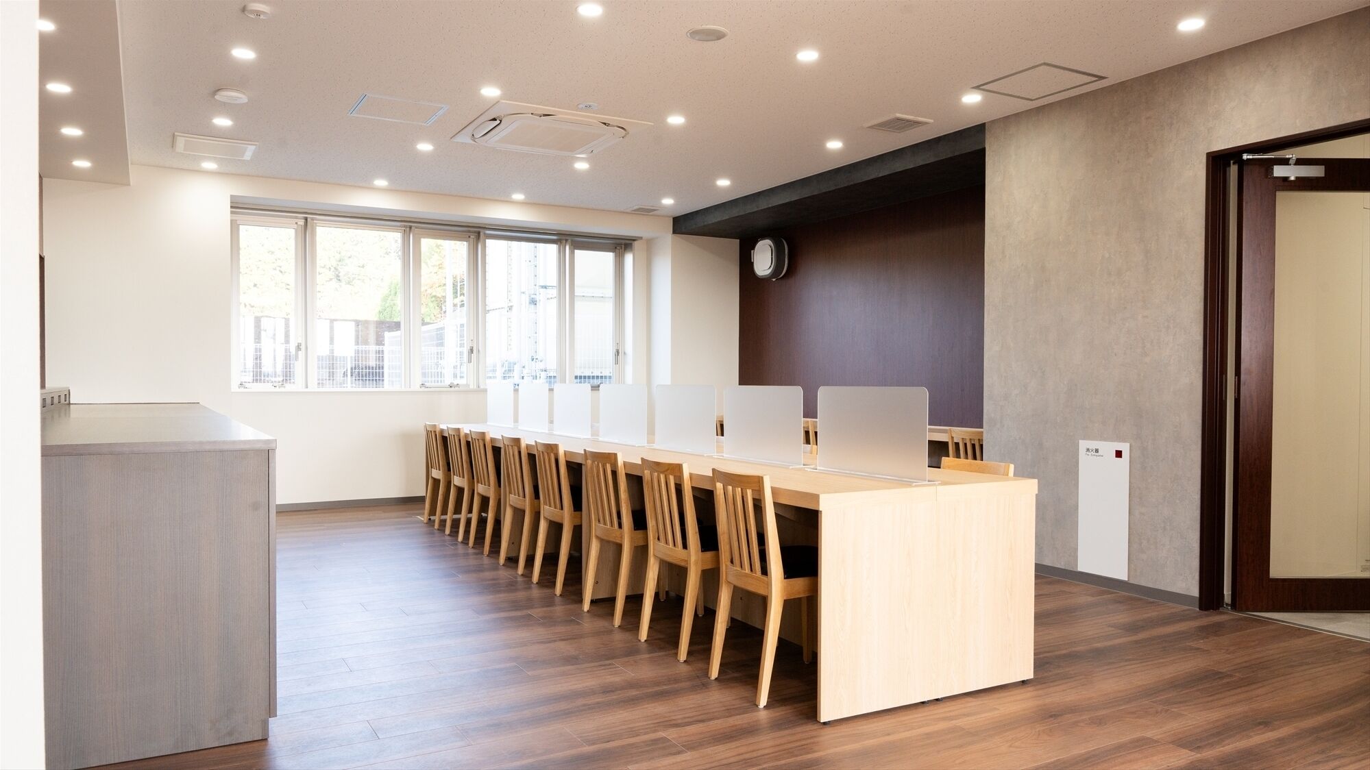 A conference room with a long table, wooden chairs, and a clock on the wall.